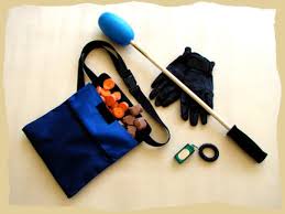 clicker training equipment. A clicker, pouch with treats, gloves and a target stick. 